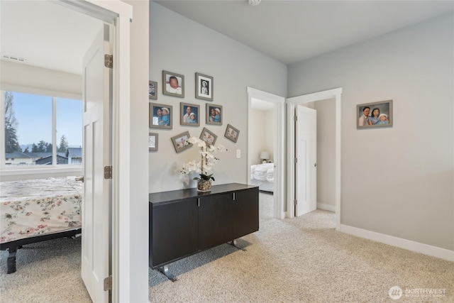 hall featuring light carpet, visible vents, and baseboards