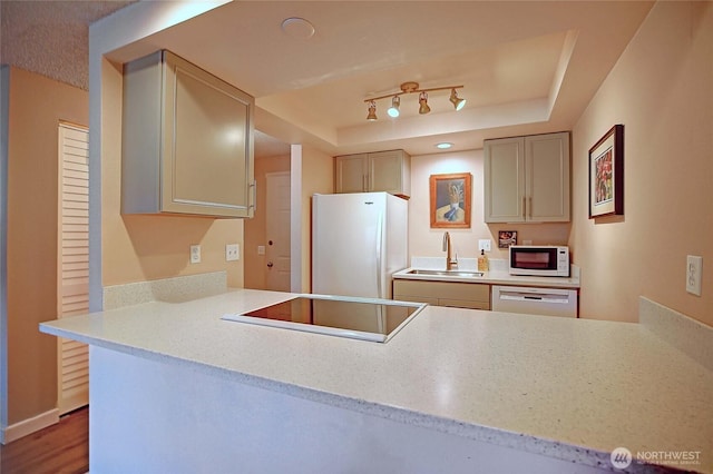 kitchen with baseboards, light countertops, a tray ceiling, white appliances, and a sink