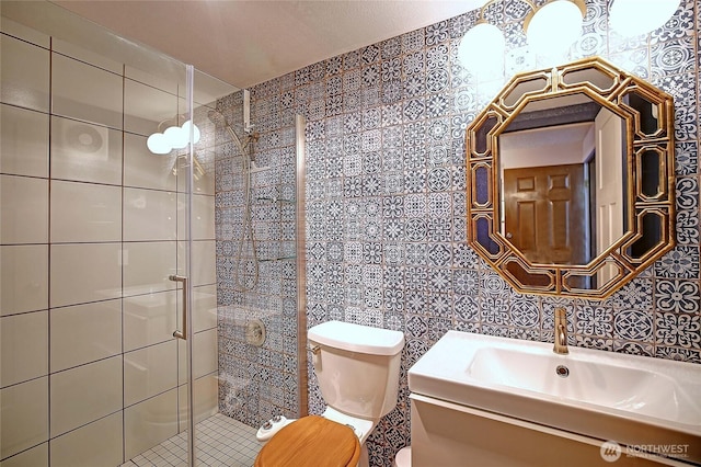 full bath featuring vanity, tile walls, toilet, and a shower stall