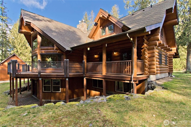 back of property featuring a lawn, roof with shingles, log exterior, and a chimney