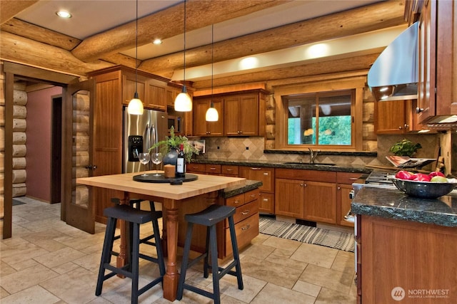 kitchen with a sink, stainless steel fridge, range hood, and brown cabinetry