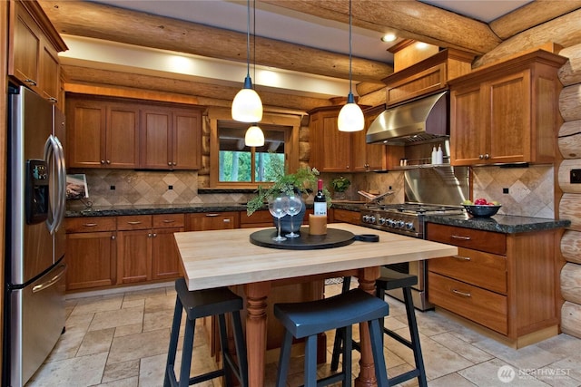 kitchen with beamed ceiling, under cabinet range hood, wood counters, stone tile floors, and stainless steel appliances