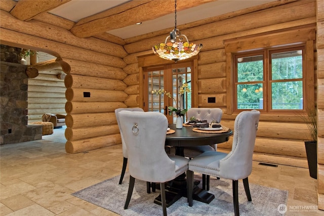 dining room featuring visible vents, beamed ceiling, stone tile flooring, rustic walls, and a notable chandelier