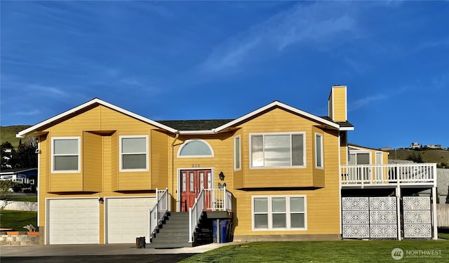 split foyer home featuring a front yard, an attached garage, driveway, and a chimney