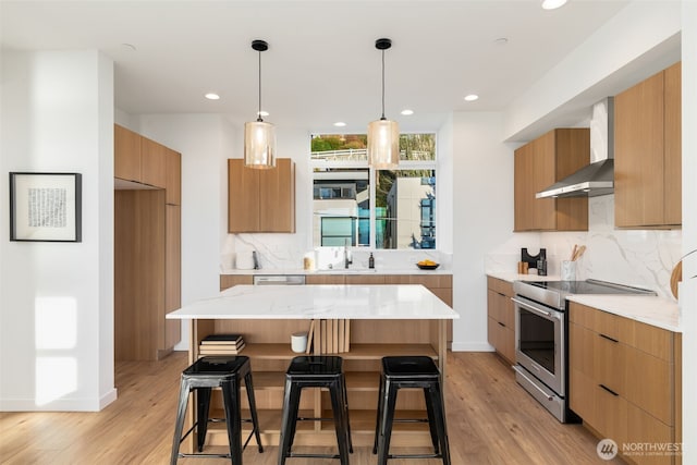 kitchen with modern cabinets, a kitchen breakfast bar, stainless steel electric range, wall chimney exhaust hood, and decorative backsplash