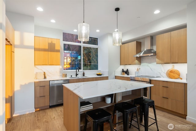 kitchen featuring a breakfast bar, a sink, appliances with stainless steel finishes, wall chimney range hood, and modern cabinets