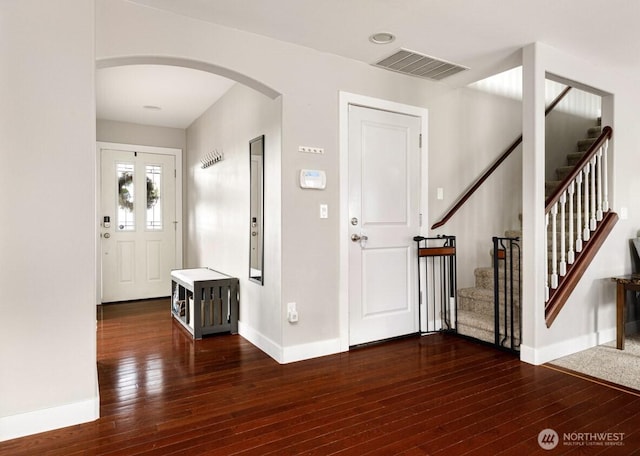 entryway featuring hardwood / wood-style floors, stairway, visible vents, baseboards, and arched walkways