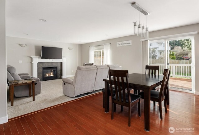 dining room featuring plenty of natural light, wood finished floors, and a tile fireplace