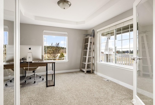 office area with visible vents, baseboards, and a tray ceiling