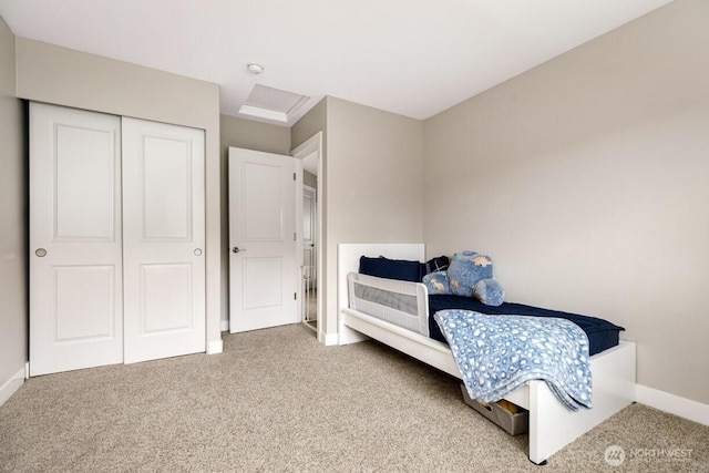 bedroom with a closet, attic access, baseboards, and carpet floors