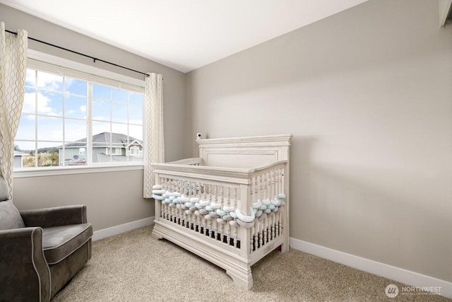 bedroom featuring a nursery area, baseboards, and carpet floors