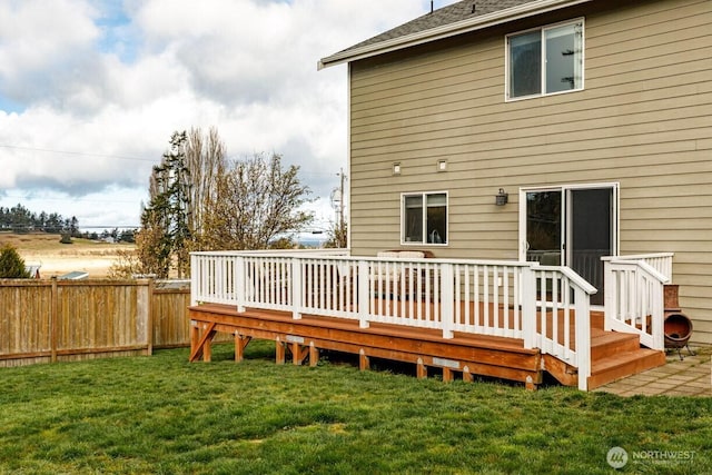 rear view of house with a deck, a yard, and fence