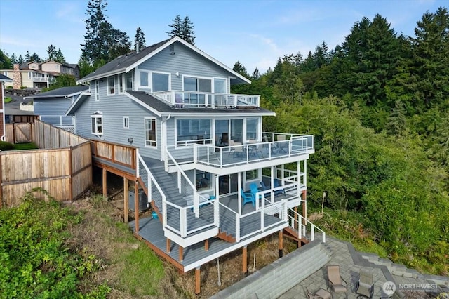 rear view of house featuring cooling unit, stairs, a balcony, and fence