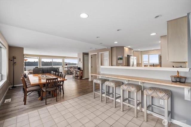 kitchen with a kitchen breakfast bar, light tile patterned floors, plenty of natural light, and freestanding refrigerator