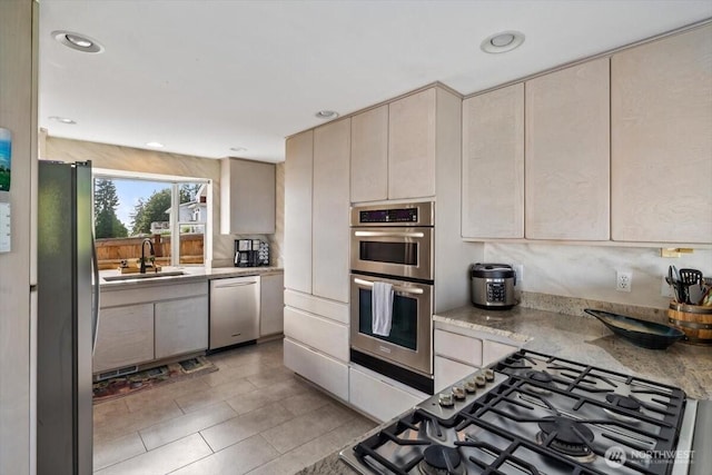 kitchen with a sink, cream cabinets, appliances with stainless steel finishes, and recessed lighting