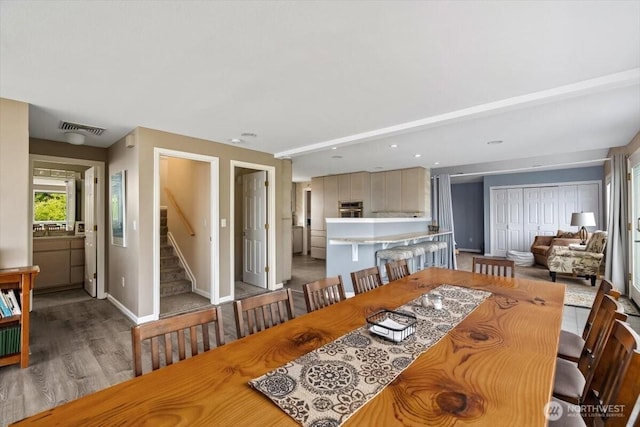 dining room with stairway, baseboards, visible vents, and light wood-type flooring