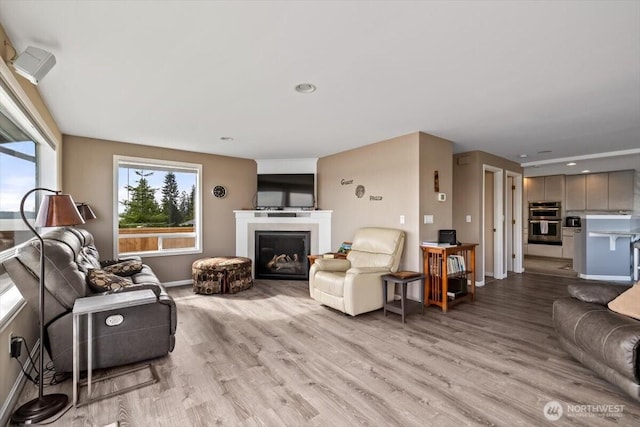 living area with recessed lighting, a fireplace, light wood-style floors, and baseboards