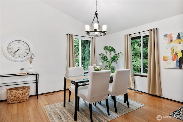 dining room featuring visible vents, a notable chandelier, light wood-style flooring, and vaulted ceiling