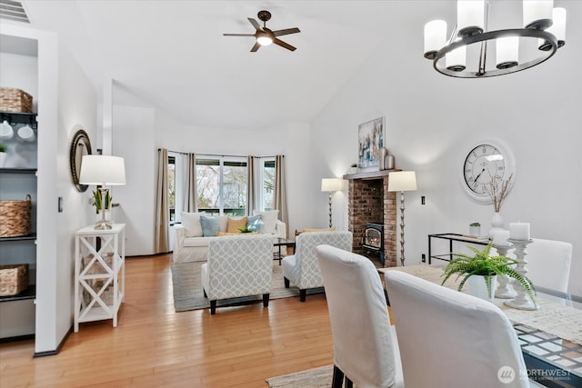 dining space with visible vents, light wood-style floors, high vaulted ceiling, and ceiling fan with notable chandelier