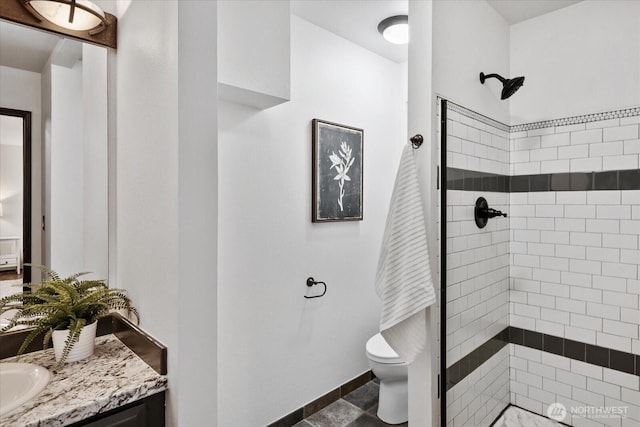 bathroom with vanity, toilet, baseboards, and a stall shower