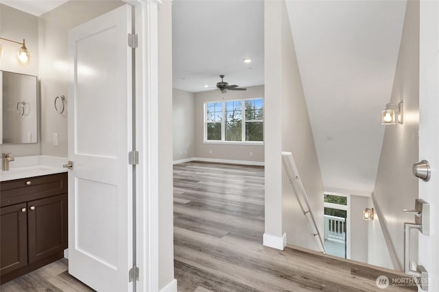 bathroom featuring vanity, wood finished floors, baseboards, and ceiling fan