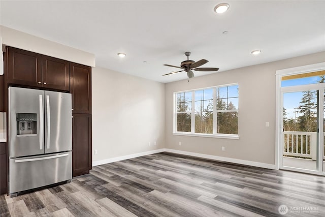 kitchen with baseboards, stainless steel fridge, dark brown cabinets, and wood finished floors