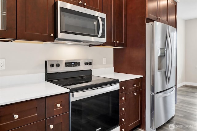 kitchen featuring light countertops, wood finished floors, baseboards, and appliances with stainless steel finishes