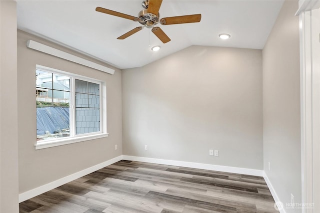 spare room with ceiling fan, baseboards, wood finished floors, and vaulted ceiling