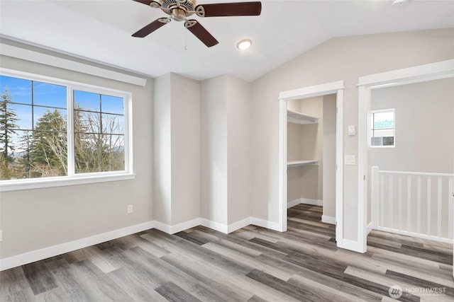 empty room with baseboards, wood finished floors, a ceiling fan, and vaulted ceiling