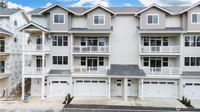 multi unit property with a garage, driveway, and a shingled roof