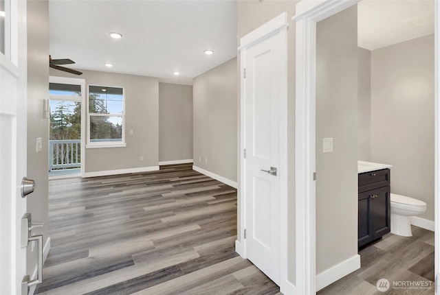 interior space featuring wood finished floors, a ceiling fan, baseboards, recessed lighting, and toilet