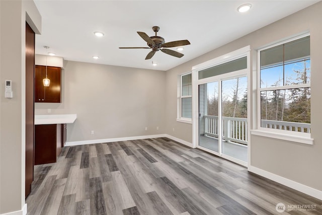 unfurnished living room featuring recessed lighting, a ceiling fan, dark wood-type flooring, and baseboards