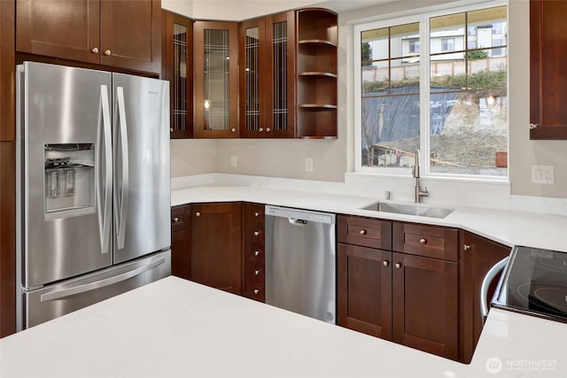 kitchen featuring a sink, light countertops, glass insert cabinets, and stainless steel appliances