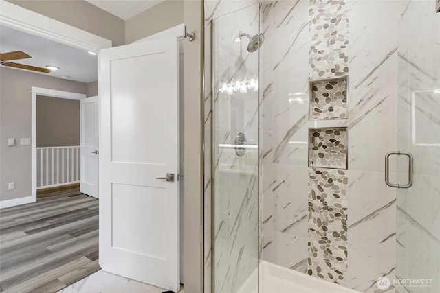 full bath featuring a marble finish shower, baseboards, and wood finished floors