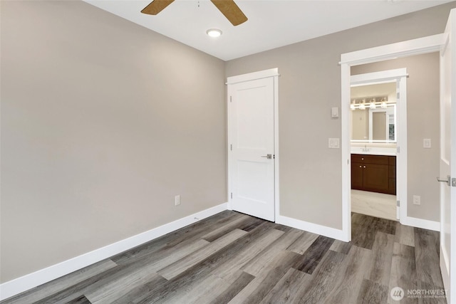 unfurnished bedroom with dark wood-type flooring, a ceiling fan, baseboards, and a sink