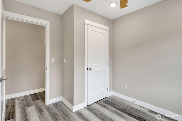 unfurnished bedroom with a ceiling fan, wood finished floors, and baseboards