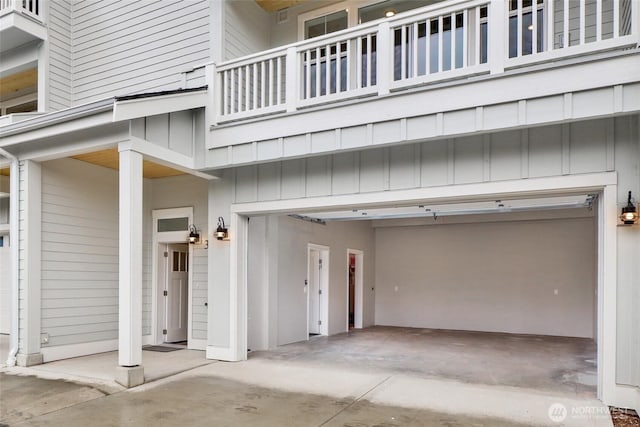 doorway to property featuring a balcony, an attached garage, concrete driveway, and board and batten siding