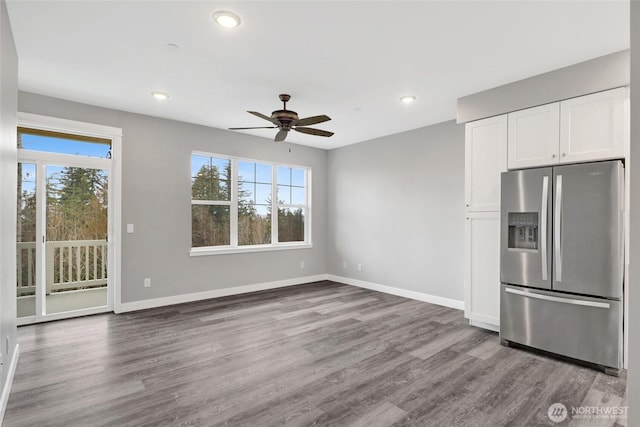 interior space with a wealth of natural light, white cabinetry, baseboards, and stainless steel fridge with ice dispenser