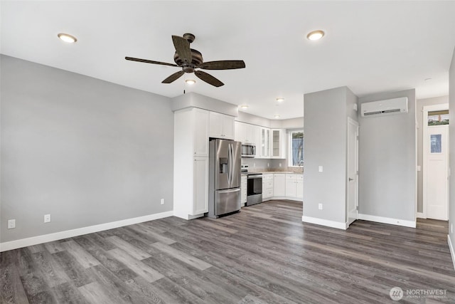 interior space with baseboards, an AC wall unit, dark wood-style flooring, and a ceiling fan