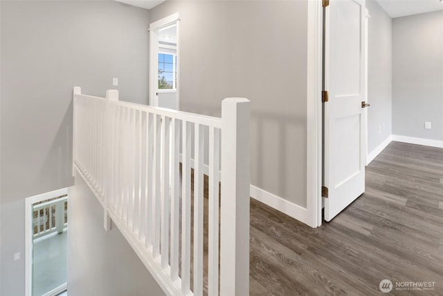 hall with wood finished floors, an upstairs landing, and baseboards