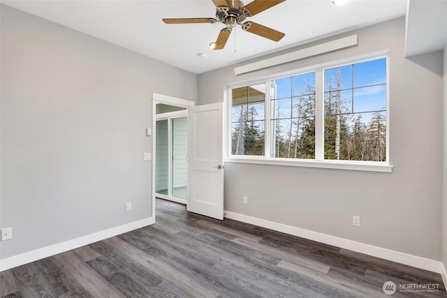 empty room featuring dark wood finished floors, a ceiling fan, and baseboards