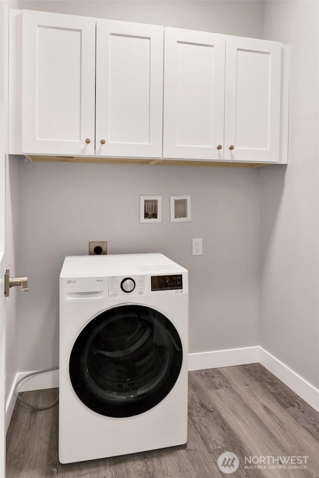 washroom featuring washer / clothes dryer, cabinet space, and baseboards