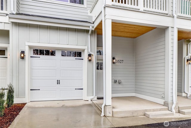 view of exterior entry with a balcony, an attached garage, and board and batten siding