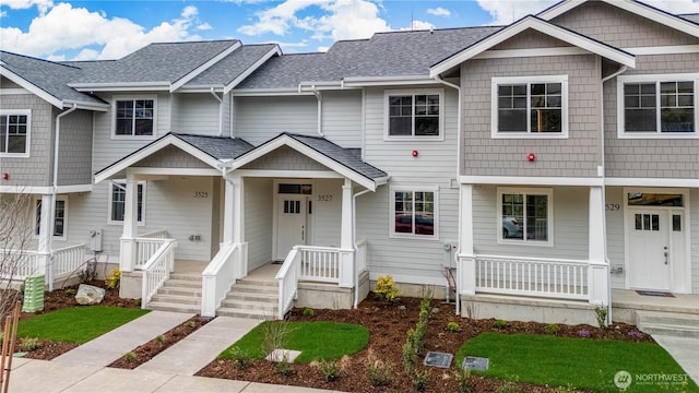 multi unit property featuring a porch and roof with shingles