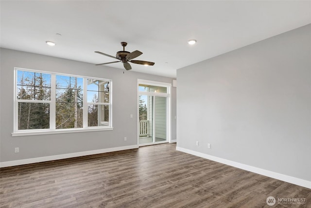 spare room featuring plenty of natural light, baseboards, and wood finished floors