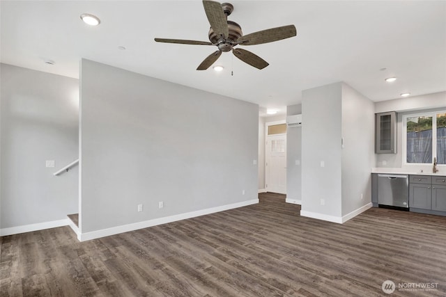 unfurnished living room featuring a sink, baseboards, dark wood-type flooring, and ceiling fan