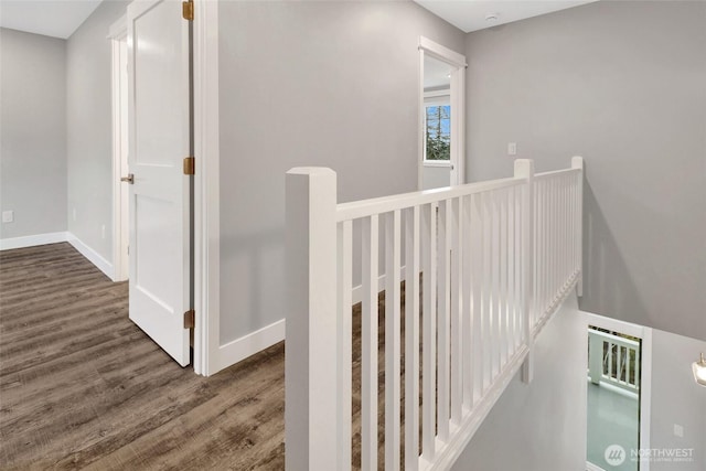 hall featuring baseboards, an upstairs landing, and wood finished floors