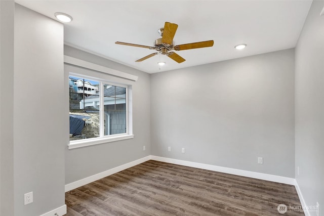 spare room with wood finished floors, a ceiling fan, and baseboards