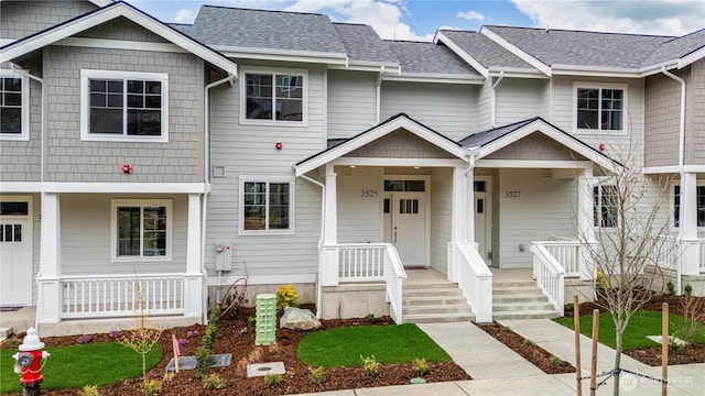 townhome / multi-family property featuring a porch and a shingled roof