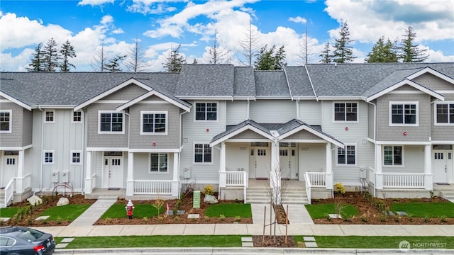 townhome / multi-family property featuring a porch and a shingled roof